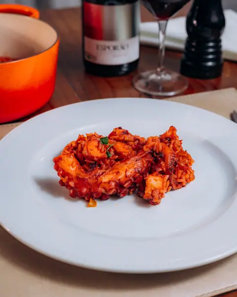 Arroz de polvo servido no prato, com vinho tinto